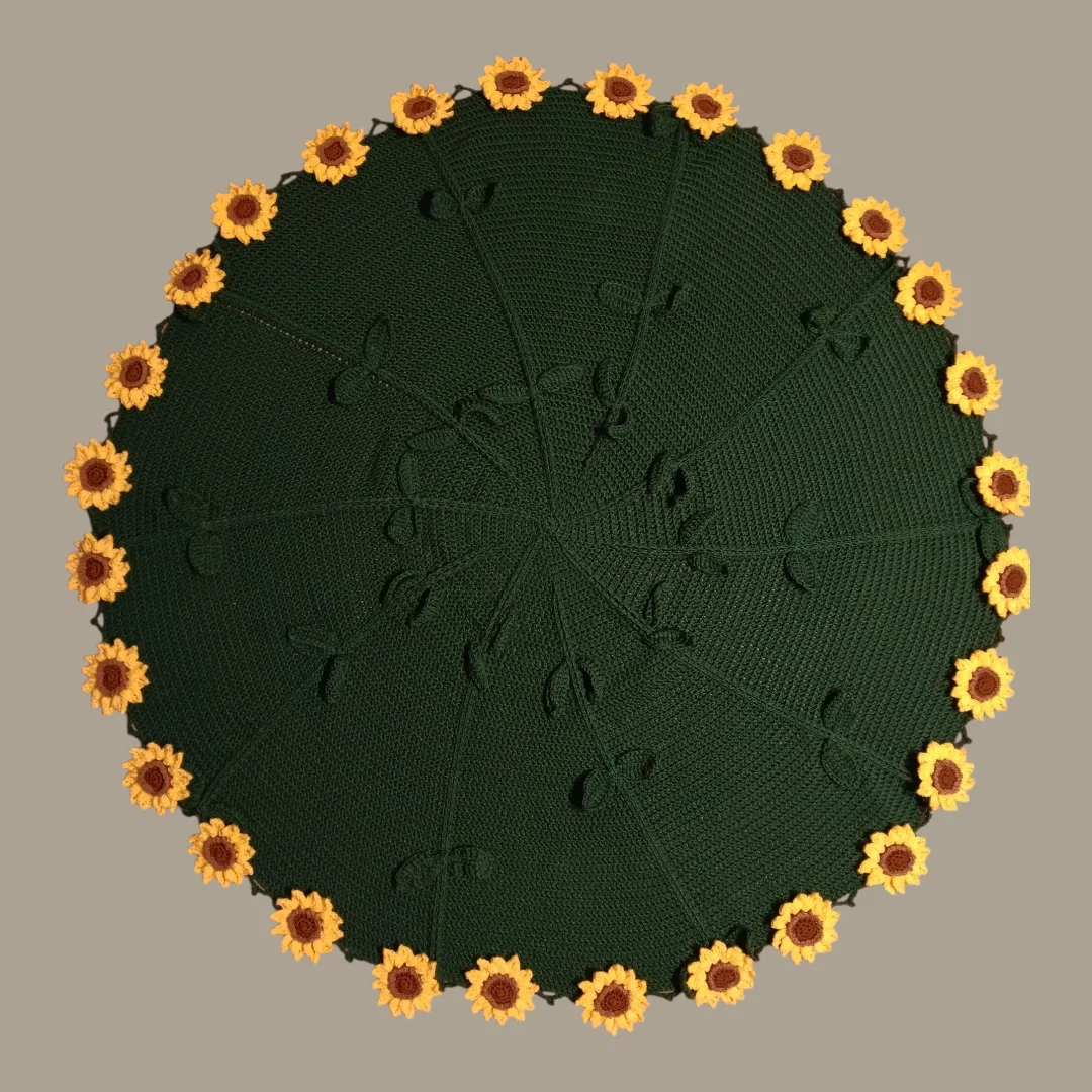 Round green crochet piece edged with yellow sunflowers, laid flat
